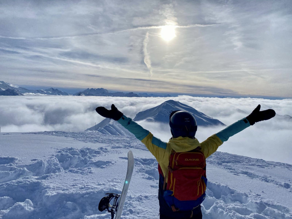 Wintersporter met handen in de lucht boven de wolken in skigebied