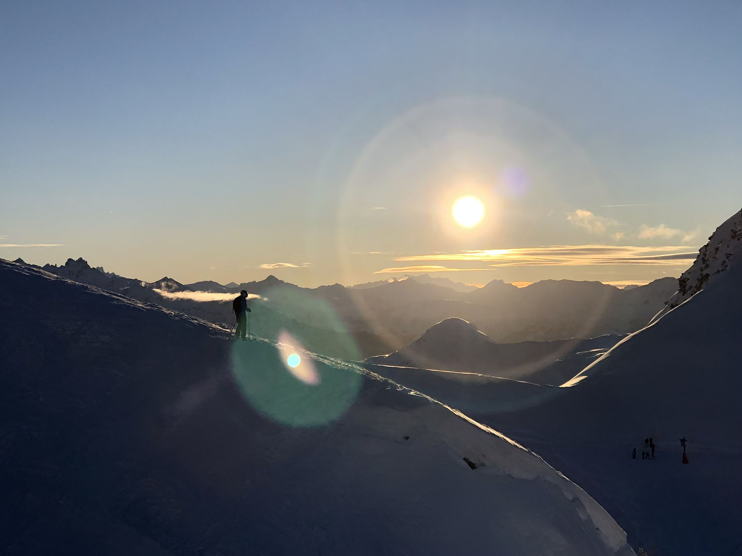 Wintersporters boven de wolken in skigebied, weerspiegeling van de zon